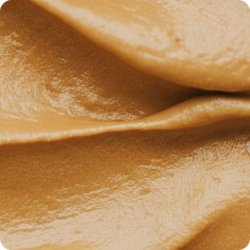 Close-up of smooth caramel sauce with glossy texture and soft folds.