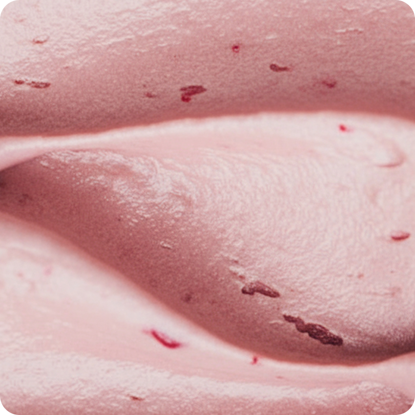Close-up of smooth, creamy strawberry-flavored pink ice cream with small strawberry pieces.